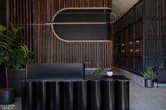 an office with black furniture and plants in the corner, along with wooden partitions