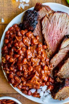 a plate with meat, beans and vegetables on it next to some chili sauces