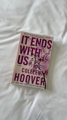 the book it ends with us by collien hoover is laying on a bed