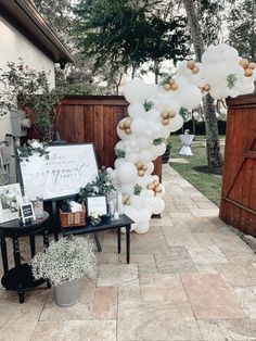 an outdoor party with white balloons and greenery