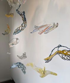 several glass objects hanging from the ceiling in a white walled room with wood flooring