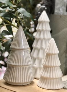 three ceramic christmas trees sitting on top of a wooden table