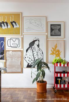 a living room filled with lots of art on the wall next to a potted plant