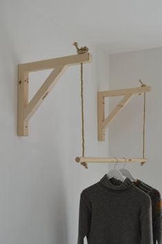 two wooden clothes racks hanging from hooks on the wall next to a sweater rack and coat hanger