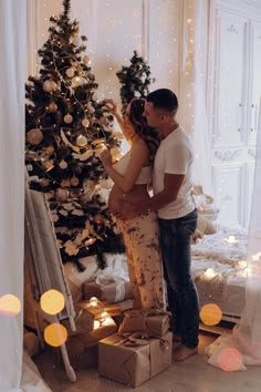 a man and woman standing in front of a christmas tree