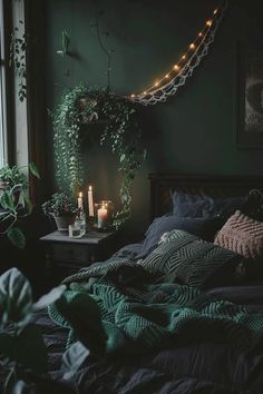 an unmade bed with candles and plants on the wall next to it in front of a window