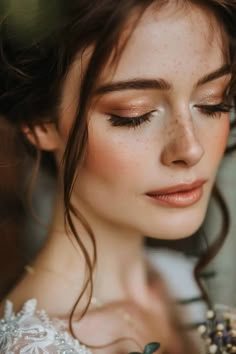 a woman with freckles on her face wearing a wedding dress and flower in her hair