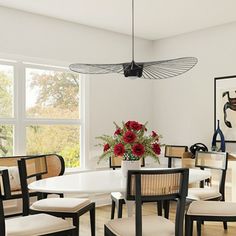 a dining room table with chairs and a vase on the table in front of it