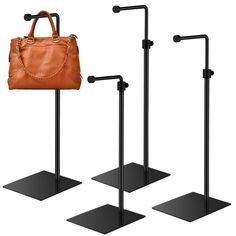 three black stands with two brown bags and one tan purse on them, all in different positions