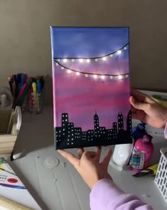 a person holding up a painting with lights on it