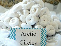 a pile of white donuts sitting on top of a table next to a sign that says arctic circles