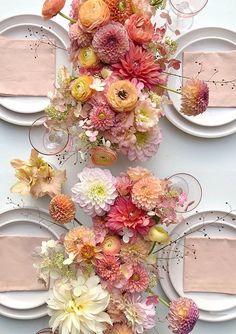 the table is set with plates, silverware and colorful flowers on top of each plate