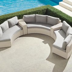 an outdoor sectional sofa with cushions next to a swimming pool