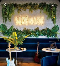 there is a neon sign that says serenanade next to two chairs and a guitar