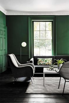 a living room with green walls and two chairs in front of the couch, coffee table