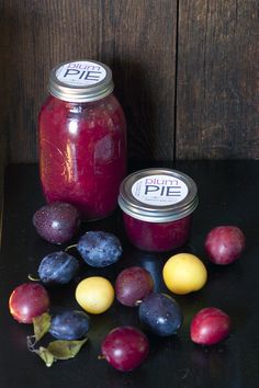 plums and blueberries sit next to a jar of pickles