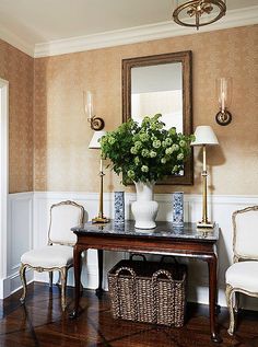 a table with two chairs and a mirror on the wall in a room that has wood flooring