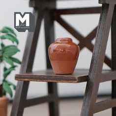 an orange vase sitting on top of a wooden chair next to a potted plant