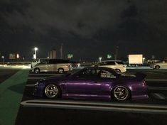 a purple car parked in a parking lot at night