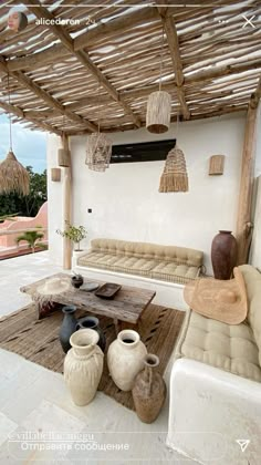 an outdoor living area with couches, tables and potted plants on the table