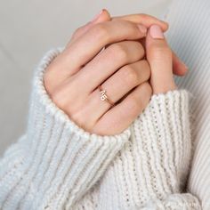 a close up of a person wearing a white sweater holding their hands together with one hand