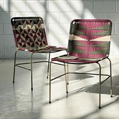 two chairs sitting next to each other in front of a white brick wall and floor