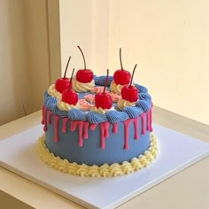 a blue cake with white icing and cherries on top