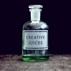 a glass bottle with a label on it that says creative juices sitting on a wooden table