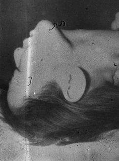 a black and white photo of a woman laying down with her hair blowing in the wind