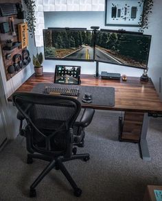 a computer desk with two monitors and a keyboard on it in front of a window