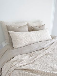 an unmade bed with white linens and pillows