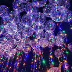 many balloons are floating in the air with lights all around them and on top of each other