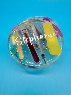 a plastic container filled with lots of different items on top of a blue surface and the words stephanie written in white