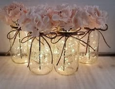 three mason jars filled with flowers and string lights