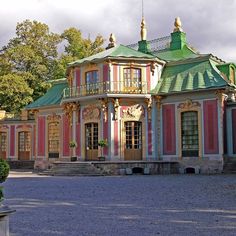 a large pink and green building with lots of windows on top of it's roof