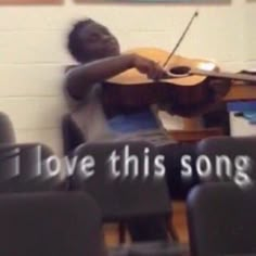 a young man playing a violin in front of a piano with words written on it