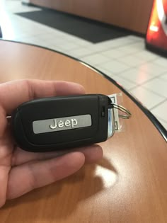 a hand holding a car key with the word jeep on it's front end