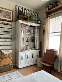 a white china cabinet sitting next to a window in a living room filled with furniture