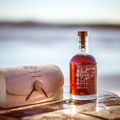 a bottle of liquor sitting on top of a wooden table next to an empty box