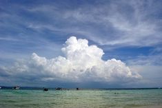 some boats are out in the water on a sunny day with blue skies and white clouds