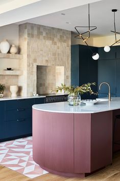 a kitchen with blue cabinets, pink countertops and an island in front of it