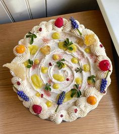 a cake decorated with fruit and berries on top of a wooden table