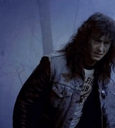 a man with long hair wearing a jean jacket