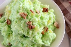 a white bowl filled with mashed potatoes covered in green frosting and pecans