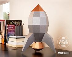 an origami model of a rocket ship on a desk next to some books