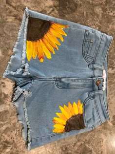 a pair of jean shorts with sunflowers painted on them