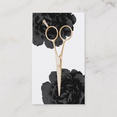 a pair of gold scissors sitting on top of a black and white flowered card