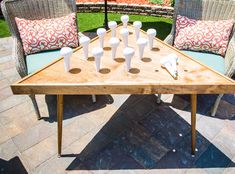 a wooden table topped with white vases sitting on top of a patio next to an umbrella