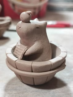 a clay figurine is sitting in a bowl