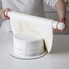 a woman is decorating a cake with white icing